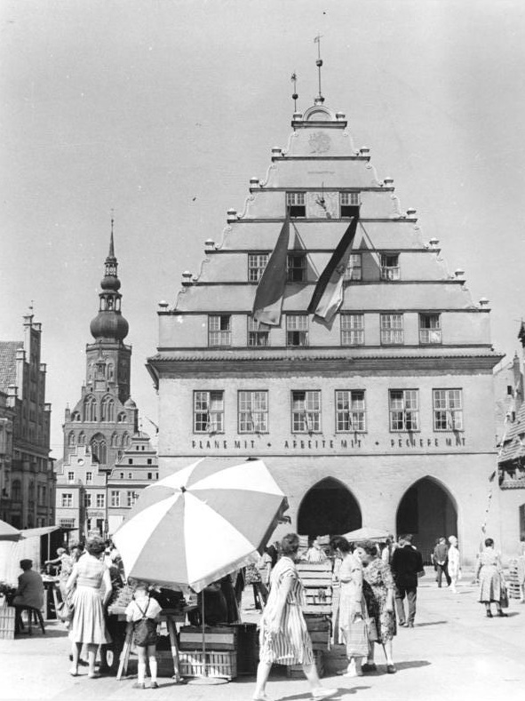 "Plane mit - arbeite mit - regiere mit": der Greifswalder Marktplatz mit Domsilhouette im Jahr 1963 (Bild: Bundesarchiv Bild 183-B0711-0003-001, CC BY SA 3.0)